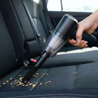 Detailing a vehicle interior with a powerful portable handheld vacuum removing dirt from the car seat.