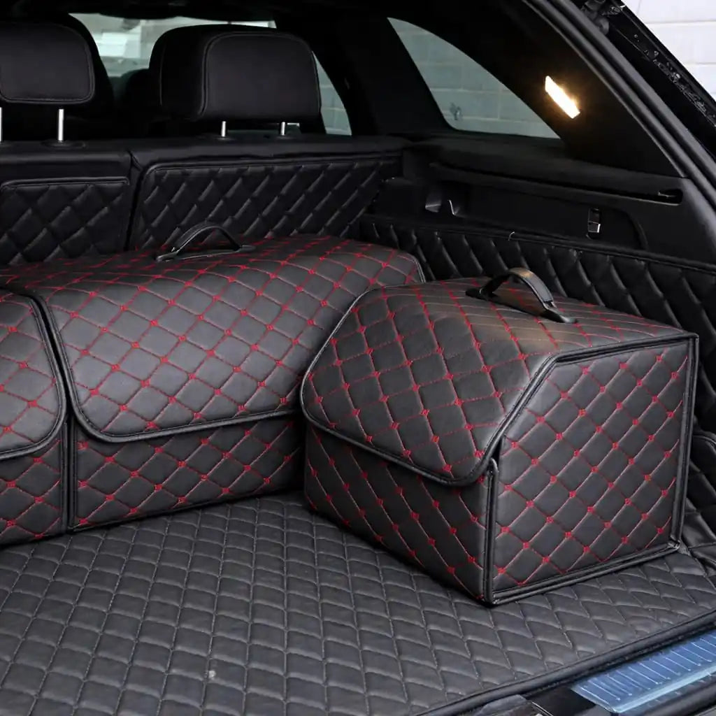 Two quilted car storage boxes with red stitching on a car trunk.