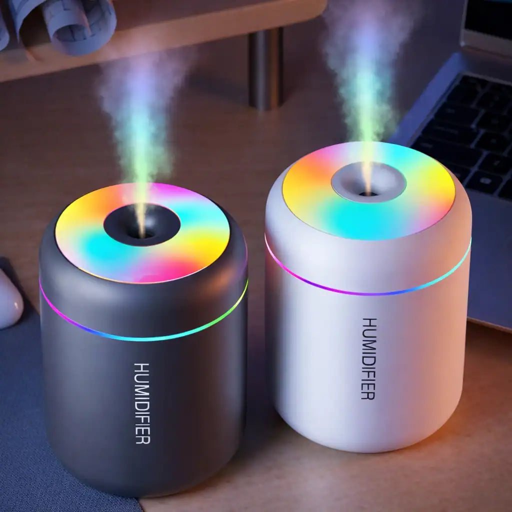 Two colorful humidifiers on a desk with steam rising from them.