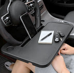 Car dashboard tray with phone, notebook, pen, and keys in a car.